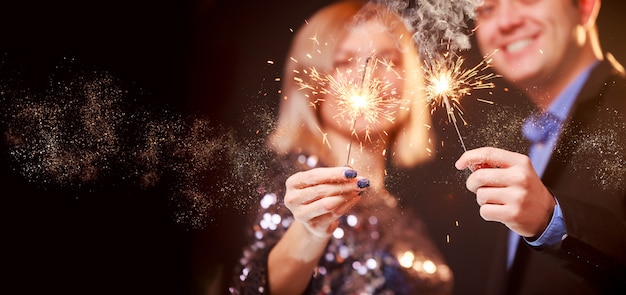 Photo of happy couple with sparklers on black background