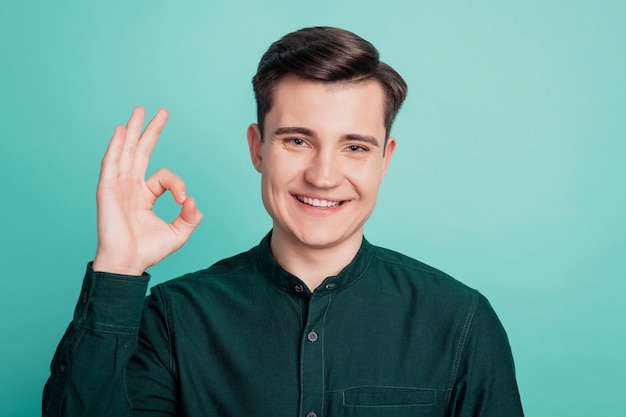 Photo of happy man showing ok-sign on turquoise background