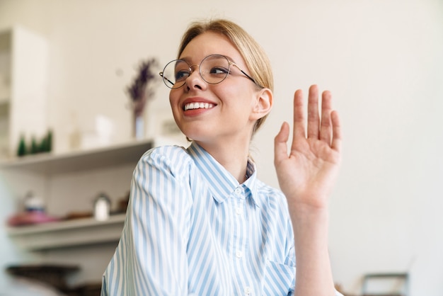 Photo photo happy nice woman architect in eyeglasses looking aside and waving hand while designing draft at workplace