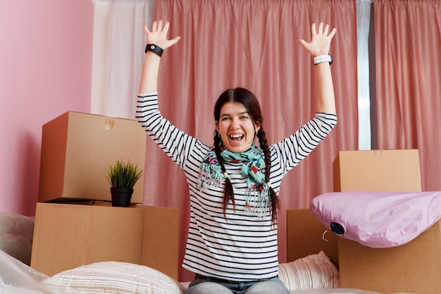 Photo photo of happy woman sitting on sofa among cardboard boxes