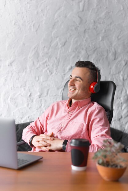 Photo of happy worker man sitting on chair relaxing and listening music or audio book