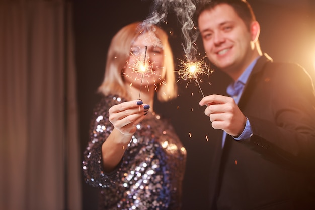 Photo of happy young couple with sparklers on black background