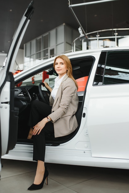 彼女の新しい車の中に座っている幸せな若い女性の写真。レンタカーのコンセプト