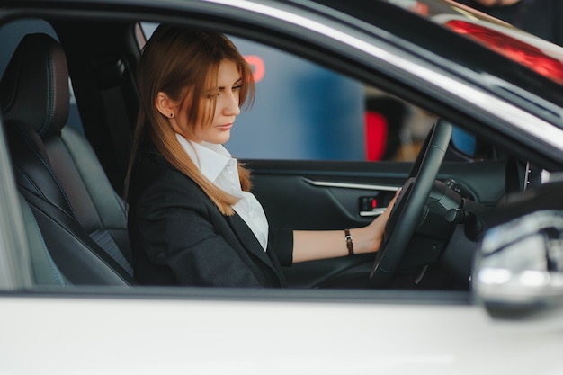 彼女の新しい車の中に座っている幸せな若い女性の写真。レンタカーのコンセプト