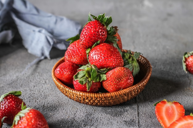 Photo of heap of fresh strawberries in the bowl on rustic grey\
background. a bunch of ripe strawberries in a wooden bowl on the\
table. copy space. healthy fresh fruit. organic food. wooden\
basket