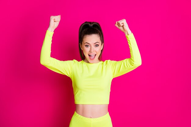 Photo of hooray pretty young lady stand fists up yell dress sport wear isolated on vibrant shine pink color background