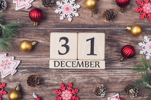 Photo image of block wood calendar showing last day of the year surrounded with newyear accessories on brown wooden timber rustic desk