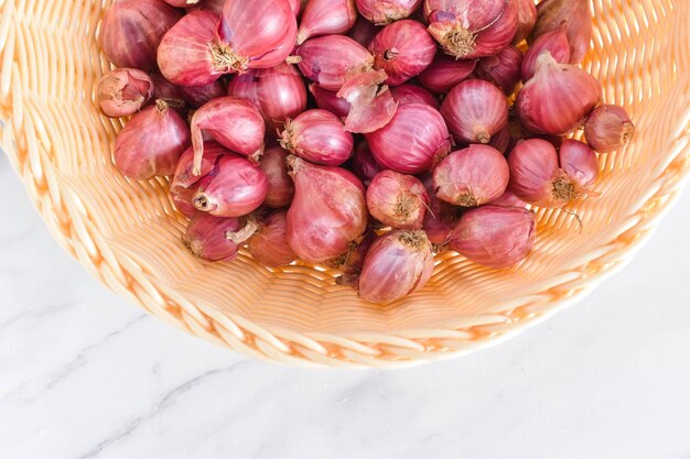 Photo photo of indonesian red onion from top angle in a rattan bowl on the white marble background