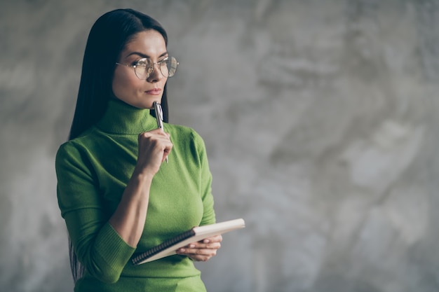 Photo of interested pondering woman thoughful thinking on her future plans holding notepad isolated grey wall concrete color background