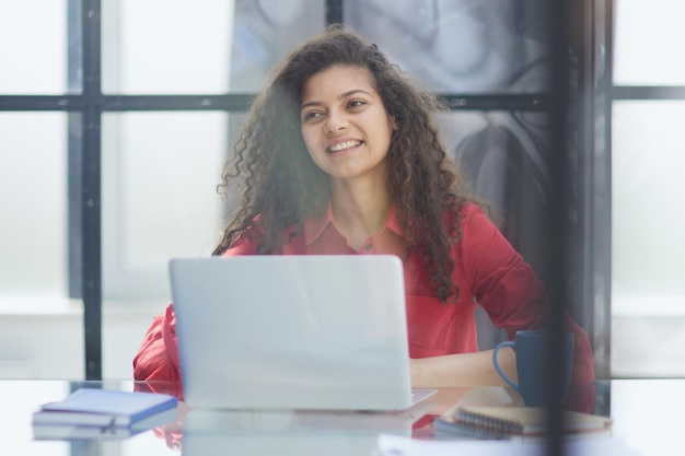 Photo of joyful nice woman using laptop and smiling while sitting