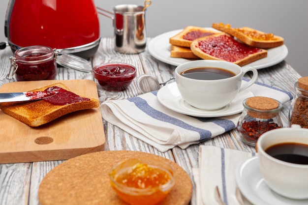 Photo of kitchen table with toasts, fruit jams and knife