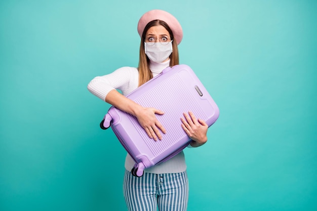 Photo of lady hug large violet suitcase afraid wear mask specs pink beret white turtleneck striped jeans isolated teal color background