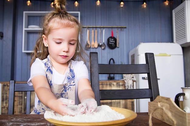 Photo of little girl cooks in the kitchen herself