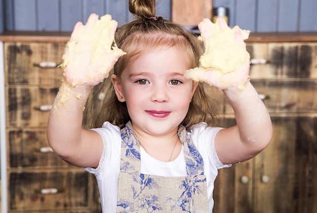 Photo of little girl shows dirty hands in dough