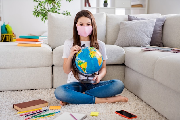 小さな生徒の女性の写真は、大きな世界の地球儀の宿題の地理を保持します