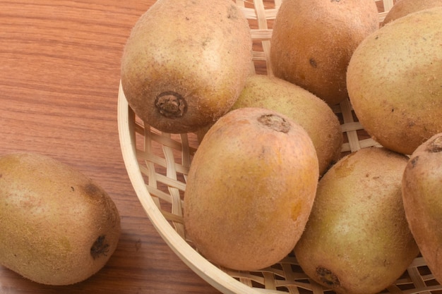 Photo of local kiwi fruit in the rattan bowl with wooden background