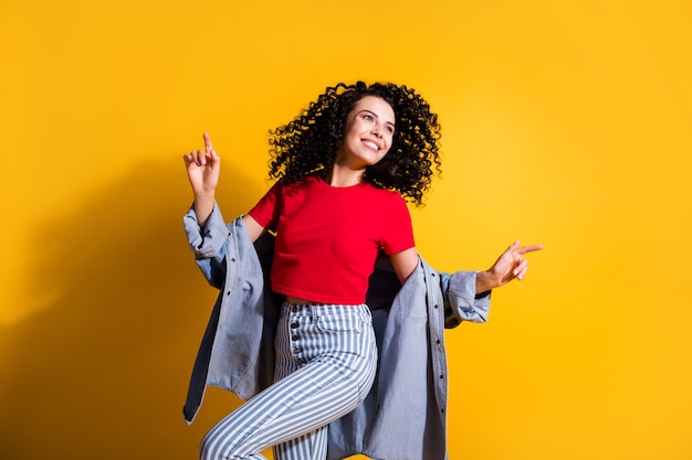 Photo of lovely girl fingers look empty space dance wear striped jeans cropped red t-shirt jacket isolated yellow color background