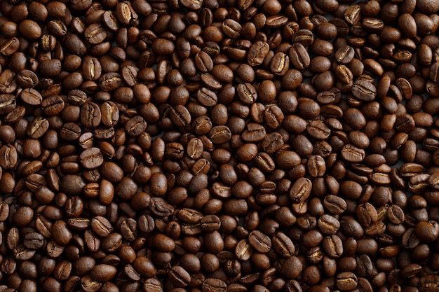 Фото макро крупным планом текстуры жареных кофейных зерен темноты можно использовать в качестве фона