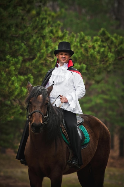 Photo male in a beautiful theater costume, on horseback in nature