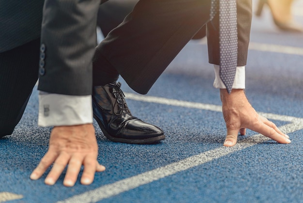 Photo of man dressed in business suit and shoes preparing to run on race track