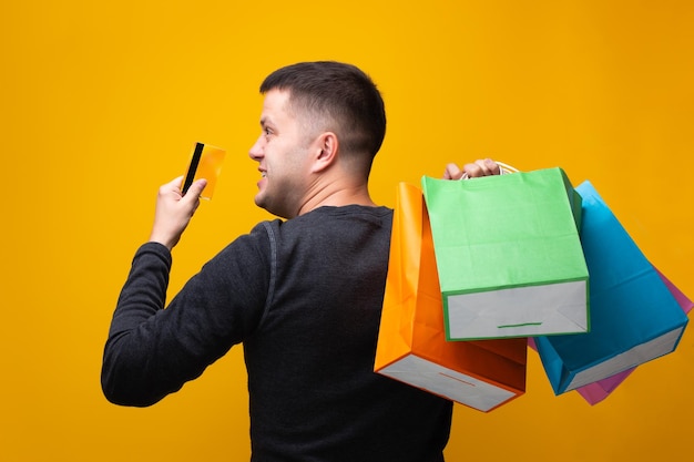 Photo of man with bank card and multicolored shopping bags