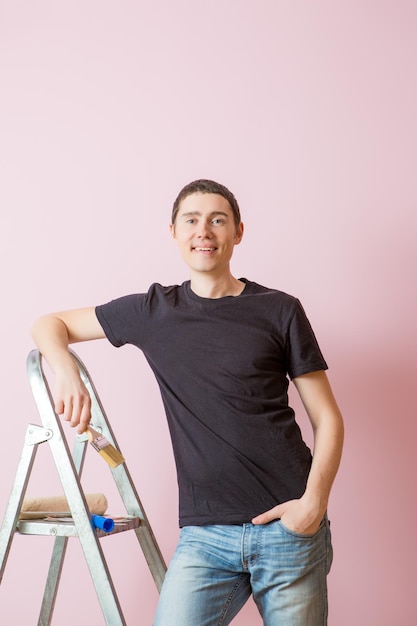 Photo of man with paint brush next to ladder