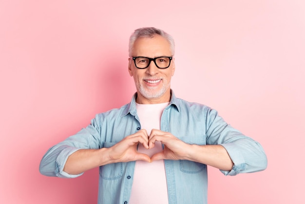 Photo of mature man show fingers heart symbol love romantic valentine day eyewear isolated over pink color background.