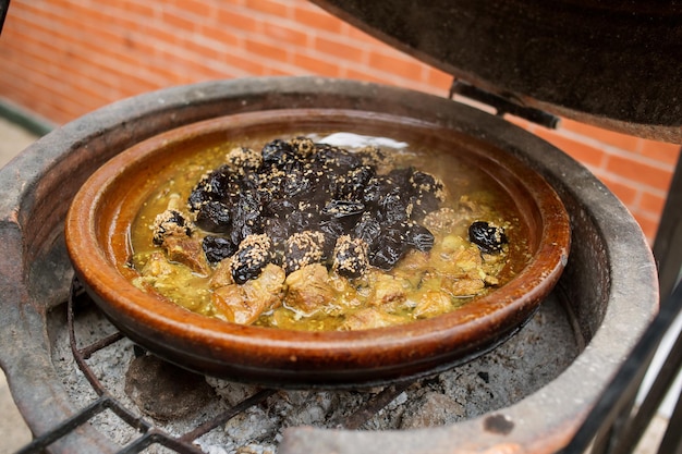 炭の上でタギンで調理された梅の肉の写真伝統的なモロッコ料理