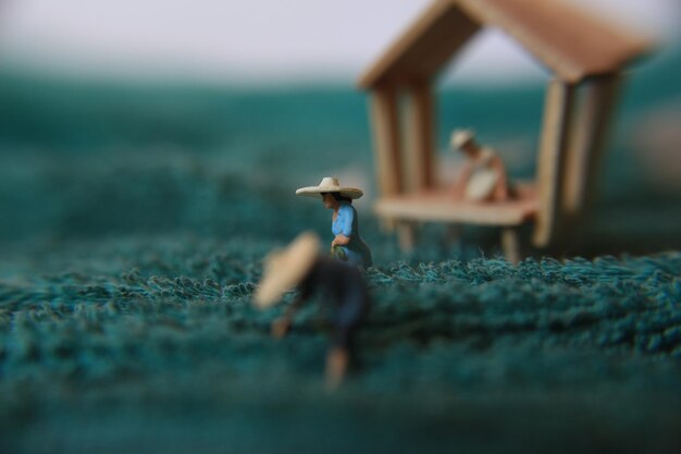 A photo of a miniature figure with the concept of a tea garden farmer who is harvesting then a women waiting at the pavilion person