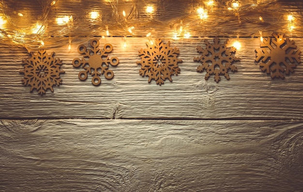 Photo of New Year's wooden golden table with burning garland from above, snowflakes.