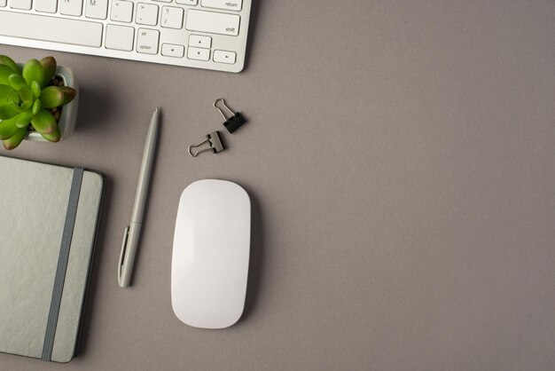 Above photo of notebook pen paperclips keyboard computer mouse and plant isolated on the grey background with copyspace