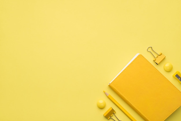 Photo above of notebook pencil and paperclips isolated on the yellow background