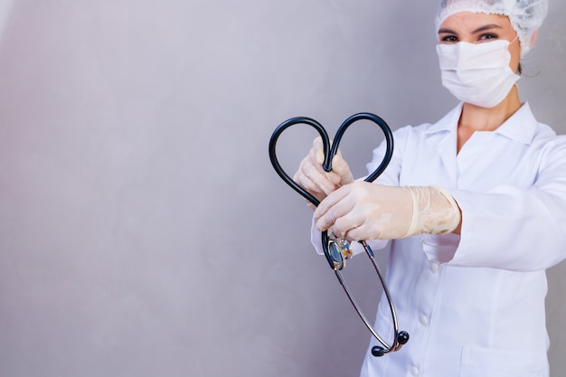 Photo of nurse holding stethoscope on gray background