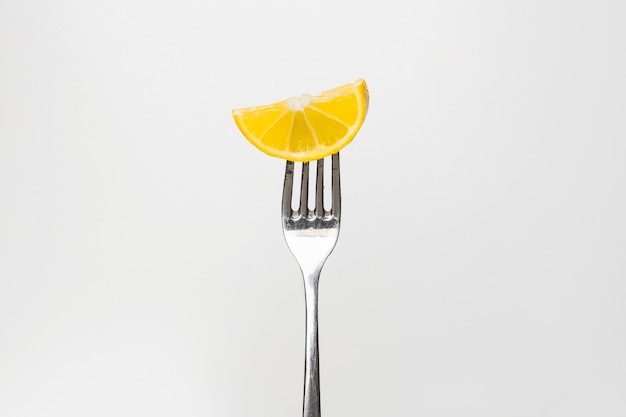 Фото Фото ломтика свежего лимона на вилке, изолированной на белом фоне