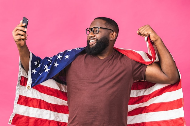 写真 陽気なアメリカのアフリカ人男性の抗議者の写真は、アメリカの国旗を上げる黒人革命は、ピンクの背景に分離された団結の連帯を表現するすべての人間を愛しています。携帯電話を使う。