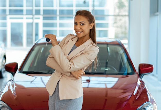 写真 彼女の新しい車のレンタカーのコンセプトの鍵を示す幸せな若い女性の写真