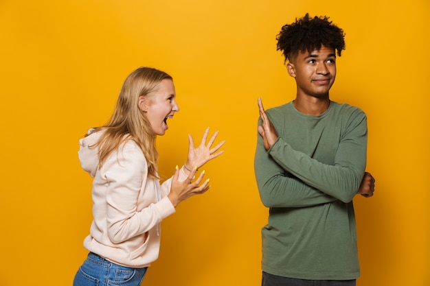 Фото Фото подчеркнутой женщины 16-18 лет, спорящей и кричащей на молодого человека, изолированной на желтом фоне
