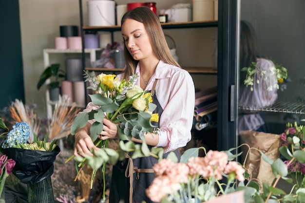 写真 花の写真を作るエプロンを身に着けている成功した現代の花屋の写真