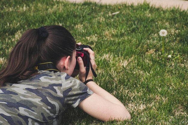 写真 草の上の花の写真を撮っている女性の写真 ストック写真