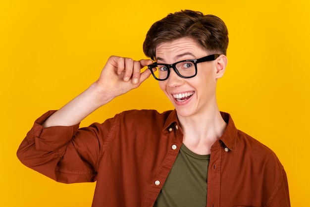 노란색 배경 위에 격리된 쾌활한 젊은 남자의 자신감 있는 손 터치 안경 비전 사진