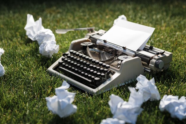 Photo of old typewriter on a green grass with a sheet of paper.