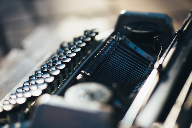 Photo of old typewriter on wooden table in sunset light, retro look.