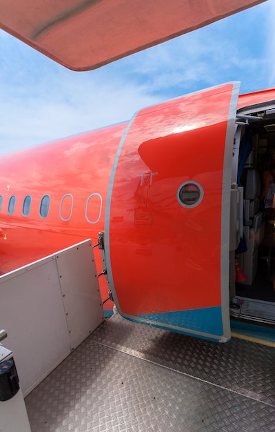 Photo of open door of big civil airplane painted in red