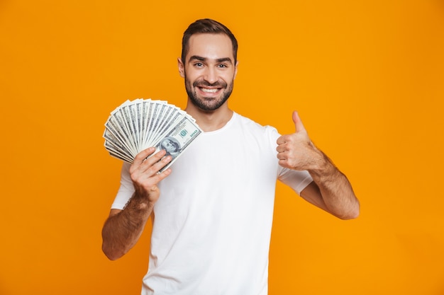 Photo photo of optimistic man 30s in casual wear holding bunch of money, isolated