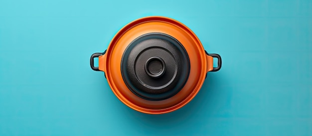 Photo of an orange pot with a black lid against a vibrant blue background with copy space