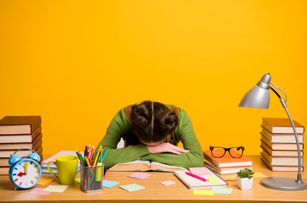 Photo of overworked girl sit table sleep isolated over yellow background