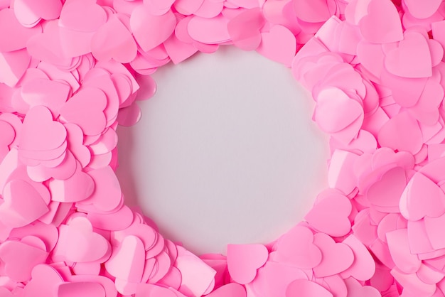 Photo of pastel pink confetti flatlay hearts background with copy space in shape of round circle space in center