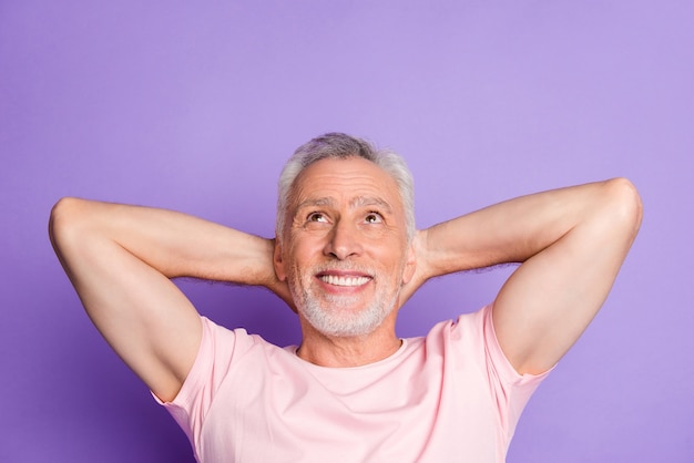 Photo of pensioner grandfather arms behind head look up empty space wear pink t-shirt isolated violet color background