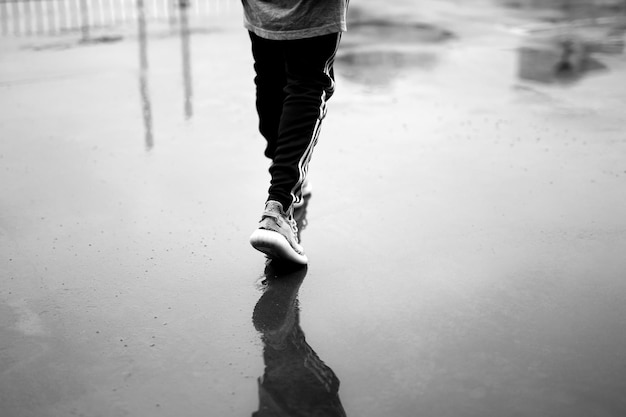 Photo of a person walking on wet asphalt.