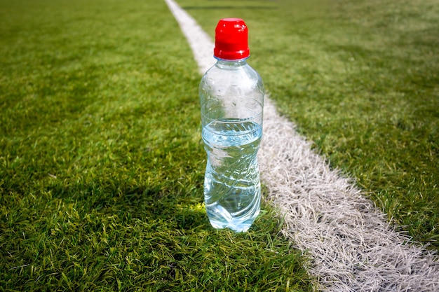 Foto di una bottiglia d'acqua di plastica sull'erba verde del campo di calcio